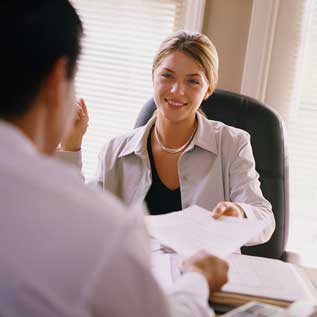 Woman at Desk taking Resume from Man