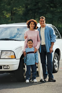 man, woman and child standing in front of a new car