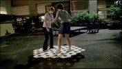 Two people standing and balancing on a wooden platform with hexagonal holes.