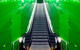 A photo of an escalator with green walls.