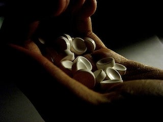 Photo of hand holding many white pills.