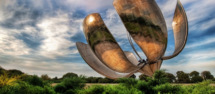 A 75-foot tall metal sculpture of a flower, standing in the middle of a park.