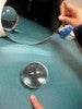 Photo of a student holding a curved mirror in front of a glass ball. 