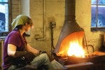 Blacksmith Amy heats metal in the forge.