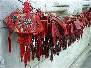A few bunches of red cards with red strings and tassels hanging on a cord on a wall. A few bunches of red cards with red strings and tassels hanging on a cord on a wall.
