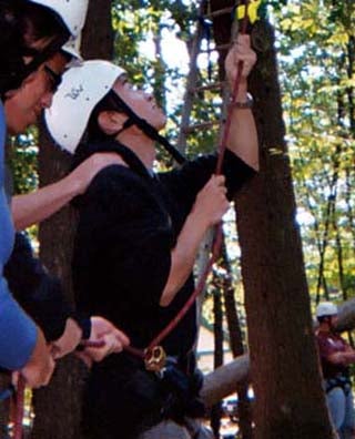 Photo of a student belaying on a ropes course.