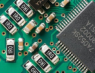 Close-up photo of a green circuit board with several connectors marked 1RO and large black square chip.