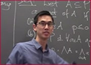 A men standing in front of a blackboard and facing front.