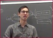 A men standing in front of a blackboard and facing front.