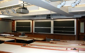 A large classroom with tiered seating and several blackboards.