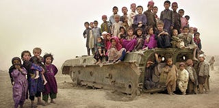 Afgani children gathering on the remains of a tank.