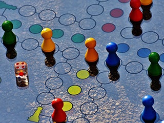 Blue and yellow board game with different colored wooden pieces and dice.