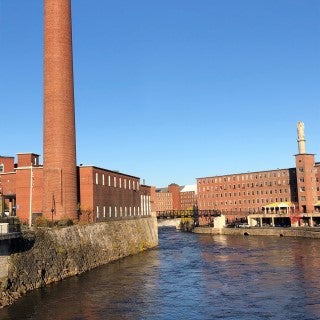 A river flanked by large brick buildings.