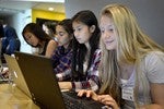 A photo of a group of girls working on their laptops.