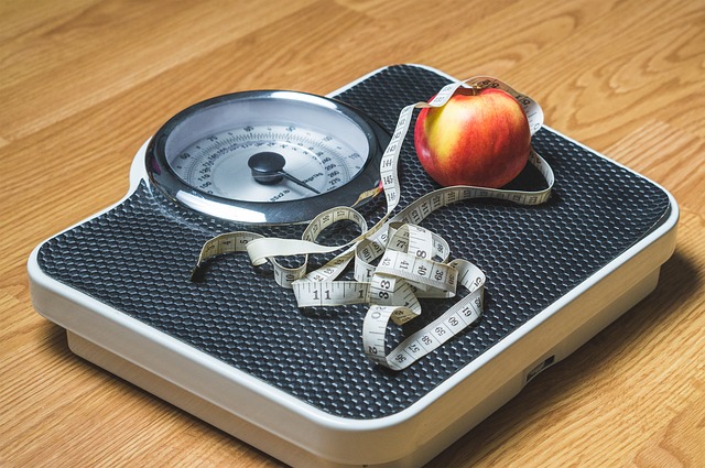 Photo of a scale, tape measure, and an apple.