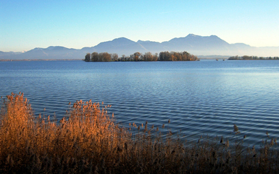 Photo of a lake with small ripples and mountains in the background.